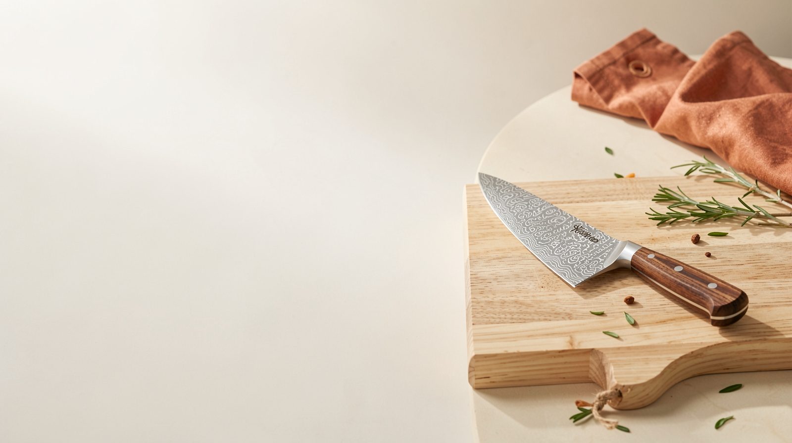 A Damascus-pattern chef's knife with a wooden handle on a pale wooden board, with rosemary beside it